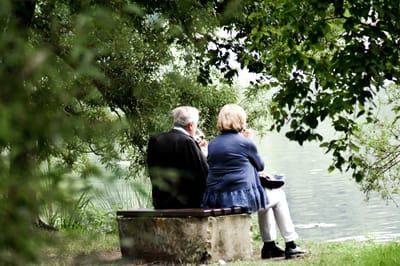 A senior couple sitting together on a bench, enjoying the outdoors